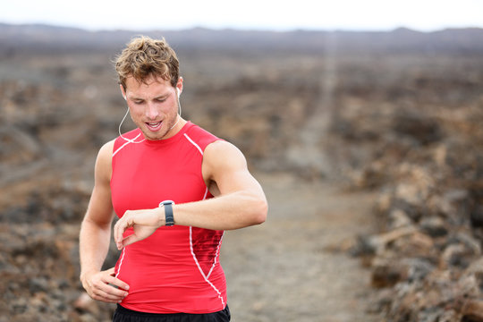 Running athlete man looking at heart rate monitor
