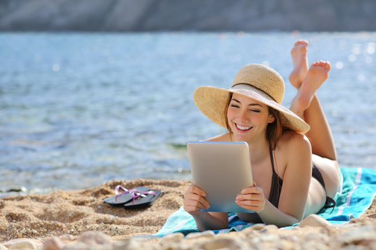 Pretty woman reading a tablet reader on the beach on vacations