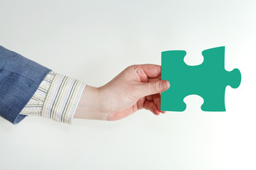 male hand holding green puzzle piece