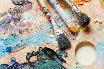 three old paintbrushes on used artistic pallette