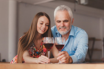 young girl and senior man holding wine glasess