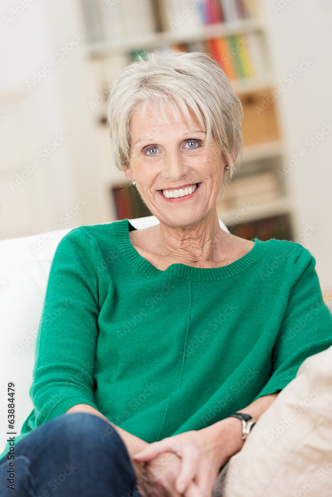 Poster seniorin sitzt entspannt auf dem sofa