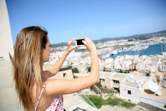 Young woman taking picture of Ibiza town scenery