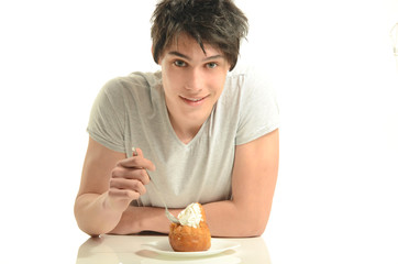 Young man eating a cream cake, man tasting sweets