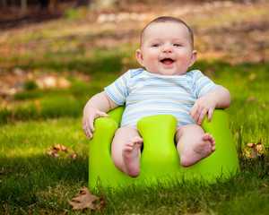 Happy infant baby boy using training seat