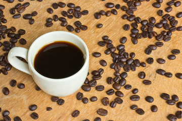 Cup of black coffee and coffee beans on wooden background.