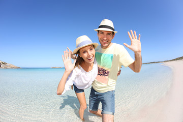 Happy couple walking in crystal clear sea water