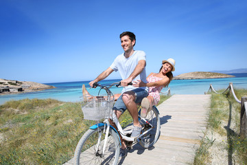 Man giving bike ride to girlfriend on beautiful Island