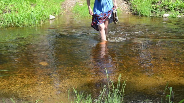 girl holds dress down to stay dry wade through the water