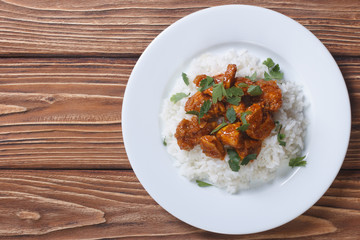 Chicken curry with rice and cilantro on a plate top view
