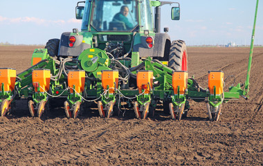 Fototapeta premium Agricultural tractor sowing and cultivating field