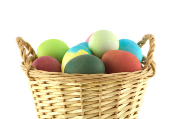 Fototapeta na wymiar Color Easter eggs in brown basket side view isolated