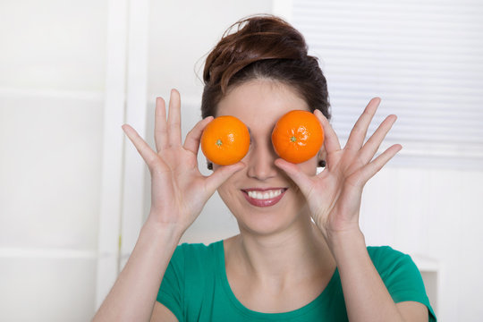 Vitamine - Frau h&auml;lt sich Mandarinen vor die Augen