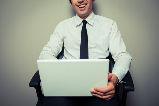 Happy young businessman in office chair