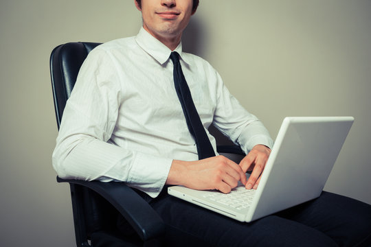 Businessman in office chair working on laptop