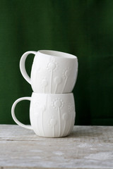 Two white cup on a green background