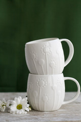 Two white cup on a green background and white flower