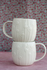 Two white cup on a pink background
