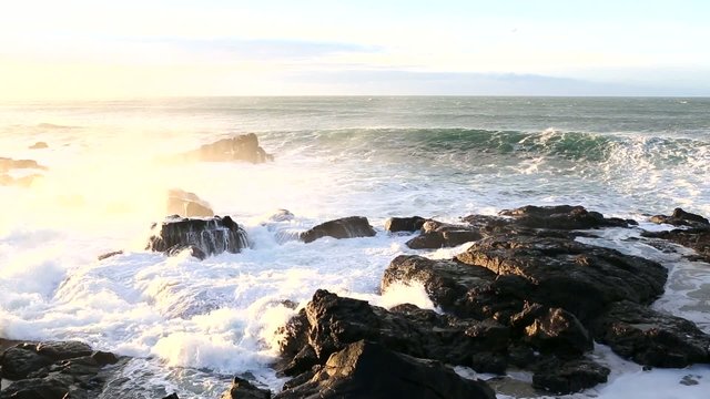 Strong sea surf in the rays of the rising sun