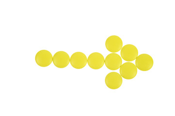 Arrow of yellow pills on white background