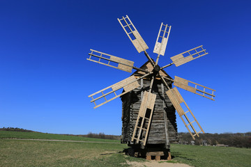 old wooden windmill on meadow