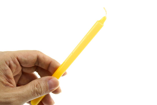 Hand hold yellow candle for lit from bottom left isolated