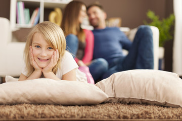 Portrait of smiling girl relaxing on carpet in living room