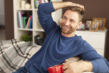 Handsome man relaxing with cup of coffee at home