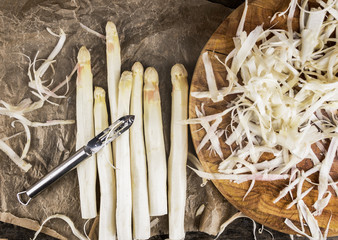 Shelled white asparagus with peelings on crumpled paper
