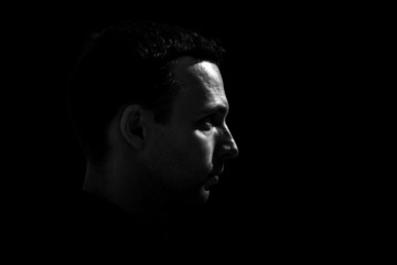 Monochrome profile portrait of young Caucasian man on black back