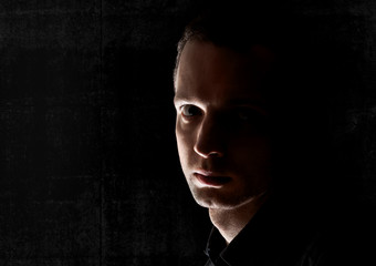 Closeup portrait of young Caucasian man in the dark