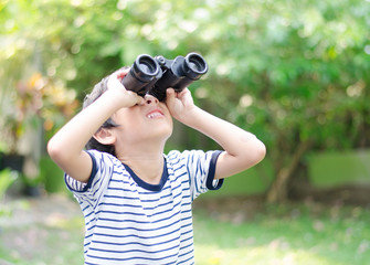 Little boy looking trough a binoculars