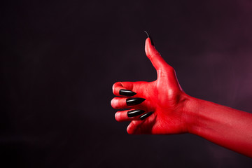 Spooky red devil hand showing thumbs up