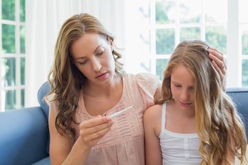 Mother looking at thermometer with sick child