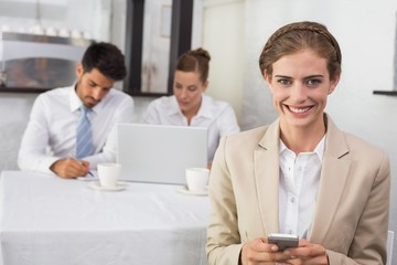 Obraz premium Businesswoman text messaging with colleagues at office desk