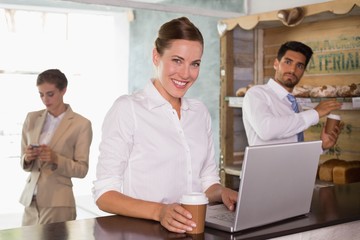 Naklejka na ściany i meble Businesswoman using laptop in office cafeteria