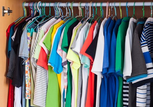 colorful t-shirts hanging in wardrobe.