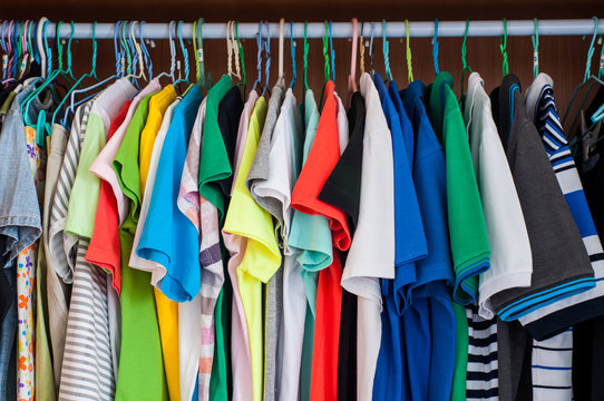 Colorful t-shirts hanging in wardrobe.