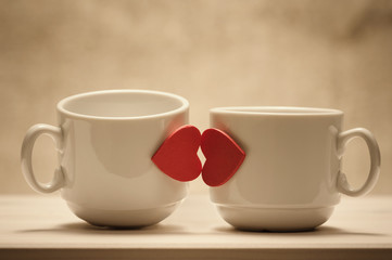Two coffee cups with red hearts as a kissing lips