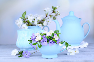 Beautiful spring flowers in cups on wooden table