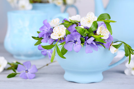 Beautiful spring flowers in cup on wooden table