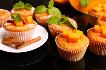 Tasty pumpkin muffins on dark background