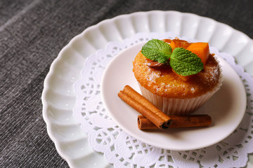 Tasty pumpkin muffin on grey tablecloth