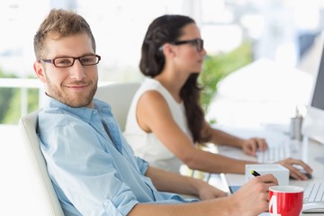 Obraz premium Handsome designer smiling at camera at desk