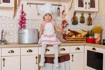 Little girl in apron in the kitchen.