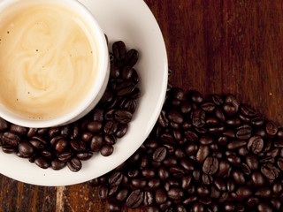Top view of a cup of dark roasted coffee with coffeebeans