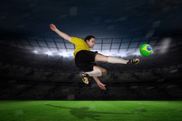 Composite image of football player in yellow kicking
