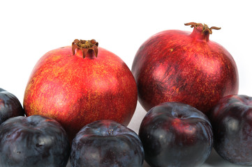 Pomegranates and plums isolated on white background