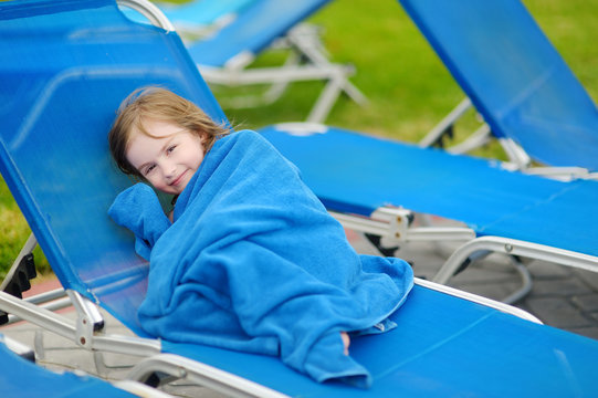 Girl covered with a towel sitting near pool
