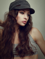 Sexy female model posing in modern cap. Vintage portrait